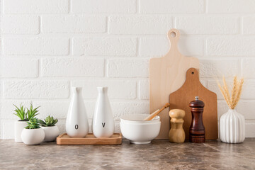 various kitchen utensils on a marble countertop in a modern kitchen. the concept of decor against the background of a white brick wall.