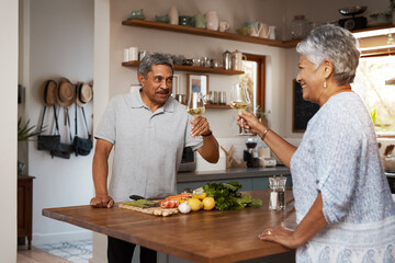 Celebrate the simple moments. Shot of a happy mature couple toasting with wine while cooking a meal together at home.