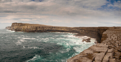 Dún Aonghasa and cliffs of Inishmore, Aran islands, county Galway, Ireland. Popular tourist landmark with stunning Irish nature scenery. Blue ocean and sky. Panorama image