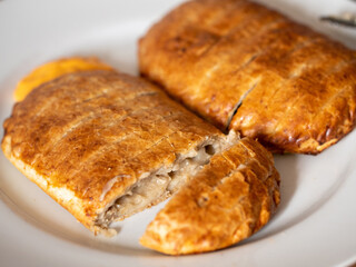 Serving of two ham and cheese pies on a white plate on wooden table. Simple food concept. Pastry product for lunch.