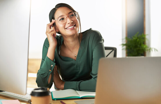 Thinking up million dollar ideas. Shot of a young businesswoman feeling happy at work.