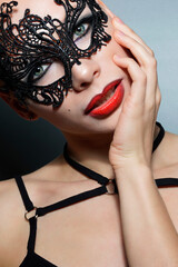 Sexy blonde woman posing in  costume and black  mask on grey  background. Halloween