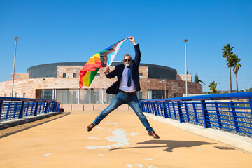 Mature gay man, executive, grey hair, beard, sunglasses, jacket and tie, jumping and waving gay...