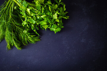 Obraz na płótnie Canvas Bunch of parsley, dill and coriander on black table