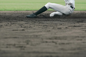 野球の試合中に盗塁を試みてベースに滑り込む野球選手