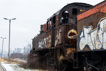 Old, rusty, demolished steam locomotive standing on the side track of the train station. Picture...