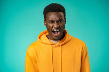 Emotional screaming young african man standing isolated over mint background