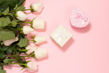Gift boxes with rose flowers on the pink background.