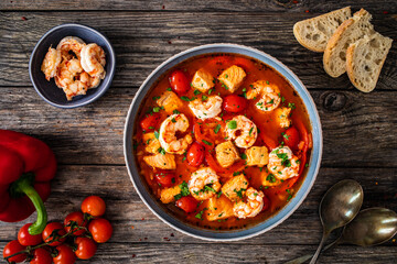 Fish soup with prawns on wooden table