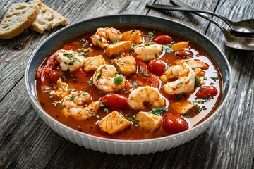 Fish soup with prawns on wooden table