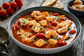 Fish soup with prawns on wooden table