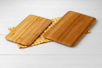 Wooden cutting board on cotton napkin on white wooden table