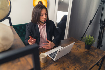 Good-looking millennial man in a suit having a call, working at home remote job concept home...