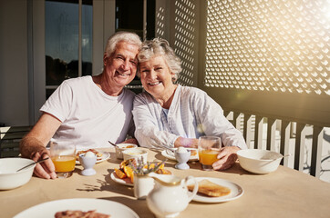 We still start our mornings together. Shot of a happy senior couple having a leisurely breakfast on the patio at home. - Powered by Adobe