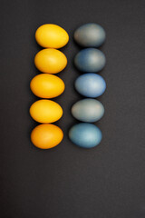 Two lines of blue and yellow Easter eggs on a black background, no war