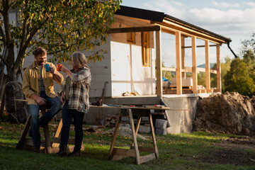 Mature couple having coffee break when working together on construction site of their new house.