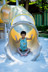 Boy playing on children's slides. Child Playing slider at outdoor summer playground. Child playing...