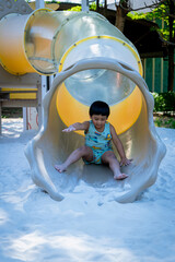 Boy playing on children's slides. Child Playing slider at outdoor summer playground. Child playing...