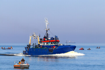 Naklejka premium Commercial fishing boat, haze on the sea. Fishermen on inflatable boats catch Baltic herring