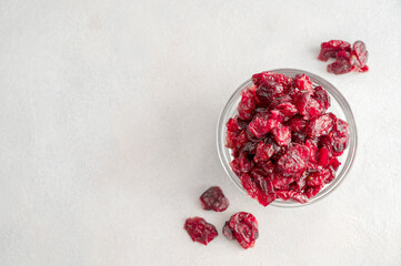 Dried cranberries in glass bowl over bright background, copy space