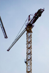 Naklejka premium Large construction site crane working on a building complex with clear blue sky.