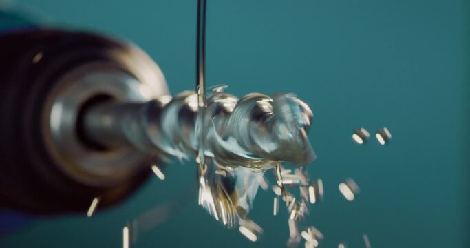 Macro shot of tip of metal drill makes circular motion with falling with oil stream during oiling process after after pickling rinsing for oxidation prevention isolated on colored background.