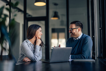 Businesswoman and man, elegantly dressed, looking at each other.