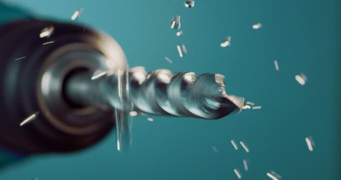 Macro shot of tip of metal drill makes circular motion with falling industrial liquid during oiling process after after pickling rinsing for oxidation prevention isolated on colored background.