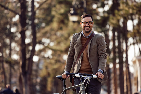 Portrait of a smiling man, pushing a bike next to him.