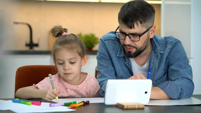 Father and kid learn to draw watching drawing lesson on tablet on internet at home. Online education concept. Video tutorial, drawing training.