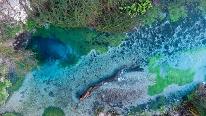 Aerial drone view of a beautiful natural spring. Wonderful natural colors of green, yellow and blue. Nature monument. Connecting with nature. Water spring. Relaxation and mediation.