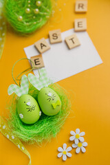 Easter composition. Easter eggs, decorative bunnies and decorations on a yellow background. Flat lay, top view, copy space