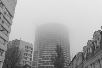 Fototapeta na wymiar Fog covers the top of the building. Fog over residential buildings