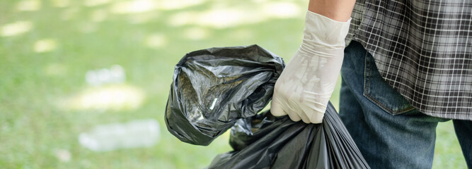 Garbage collection, Man's hands pick up plastic bottles, put garbage in black garbage bags to clean...