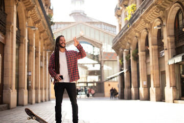 Portrait of young handsome guy with skateboard. Happy smiling skater using the phone.