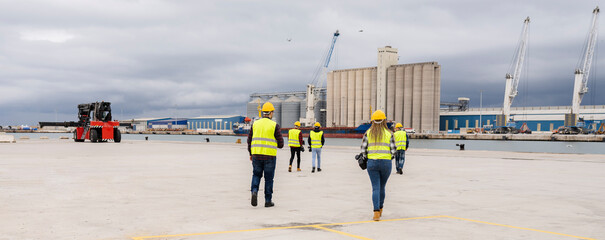 group of logistics workers at port walking rear view - wear virtual reality goggles to work