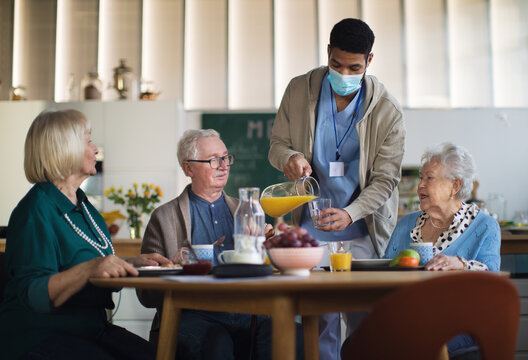 Group of cheerful seniors enjoying breakfast in nursing home care center.