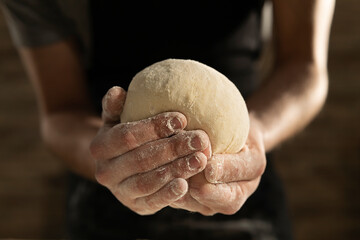 Cinematic close up of professional artisan baker chef is making with flour loaf of dough for preparation of pasta, pizza and other pastries in rustic bakery kitchen.