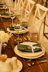 A wooden table without a tablecloth is served and decorated with fresh flowers. Outdoor cafe.