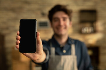 Cinematic shot of smiling artisan baker is showing in camera smartphone for online commerce...