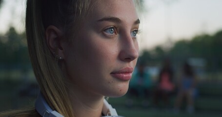 Cinematic close up shot of young blond hair woman is having fun to listening to the music with earphones and dancing on basketball outdoor court after finishing friendly game match at sunset.
