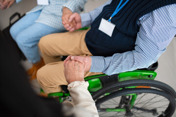 Obraz premium Close-up of senior man sitting in wheelchair at group therapy session.