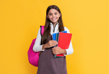 happy child with school bag and workbook on yellow background