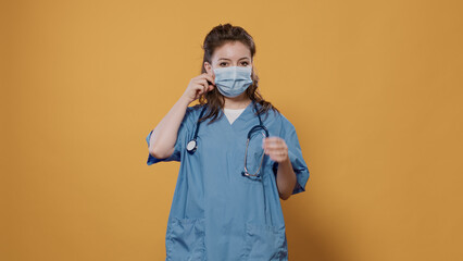 Medical doctor standing posing confident with arms crossed removing surgical mask in medical...