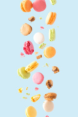 Colorful macarons biscuits float in the air on a pastel blue background. Surreal sweet food aesthetic concept. Creative wallpaper