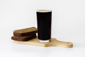 a mug of kvass and slices of rye bread on a wooden tray on a white background, traditional Russian...