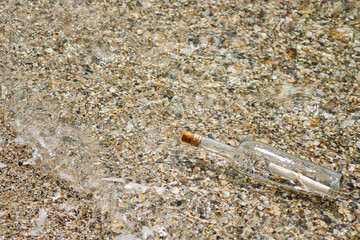 A bottle with a letter thrown out of the sea on a sandy shore.