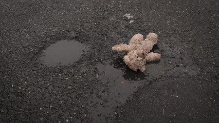 Child Abuse, family violence, orphanage concept: teddybear falling in the street. Snow, dark urban setting. Slow motion
