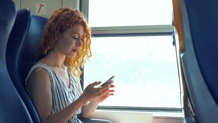 traveling by train - woman sitting on train smiling reading a message on phone - Powered by Adobe