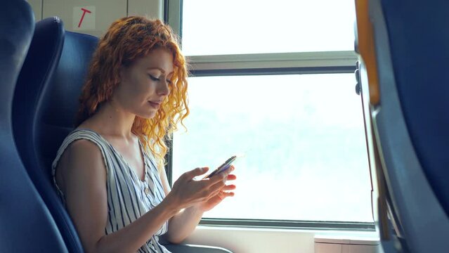 Traveling By Train - Woman Sitting On Train Smiling Reading A Message On Phone